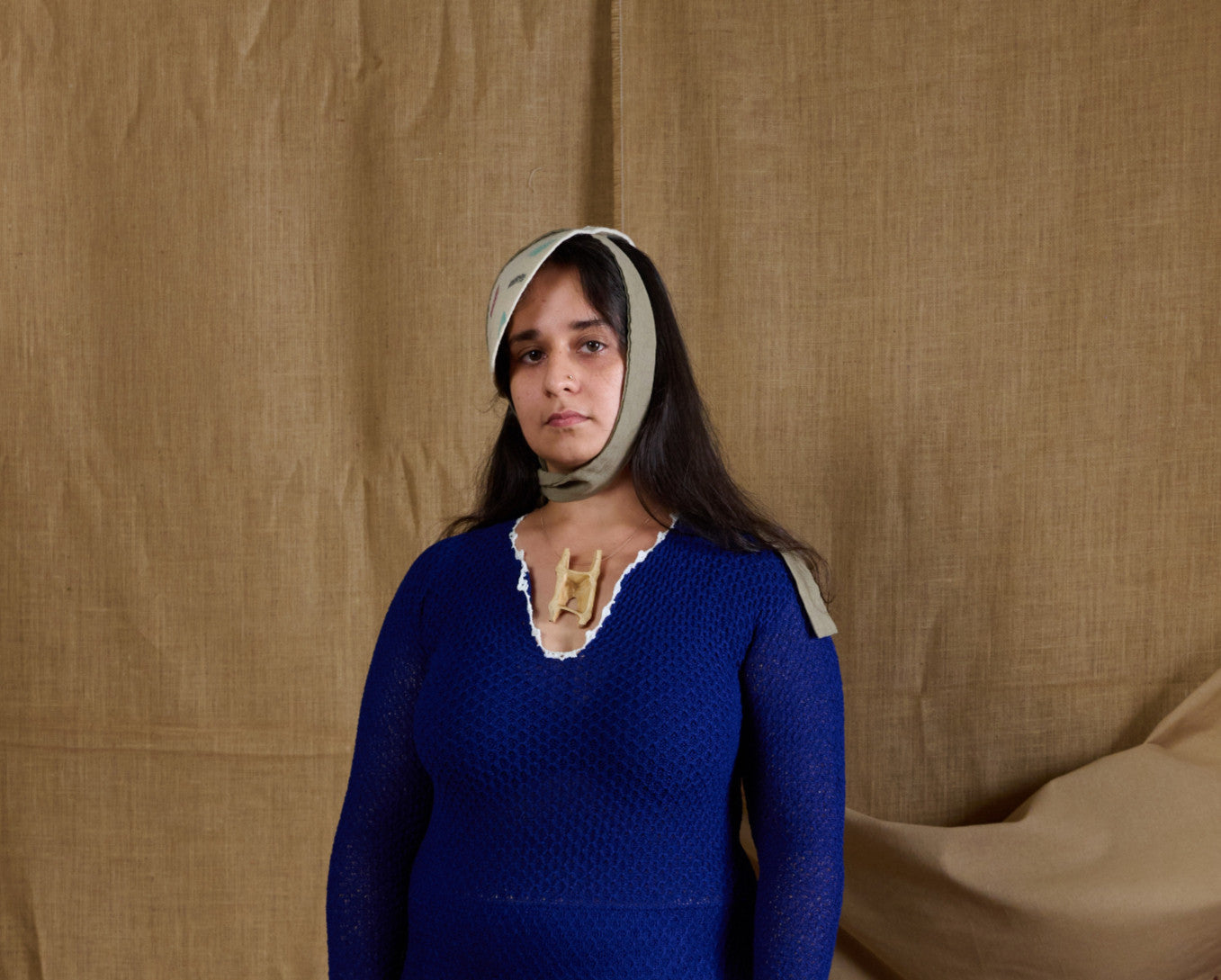 A woman wearing an off-white tieable hat with a geometric pattern, standing against a textured background. Andrea Viêntëc - Off-White Tieable Hat sold by two extra lives 