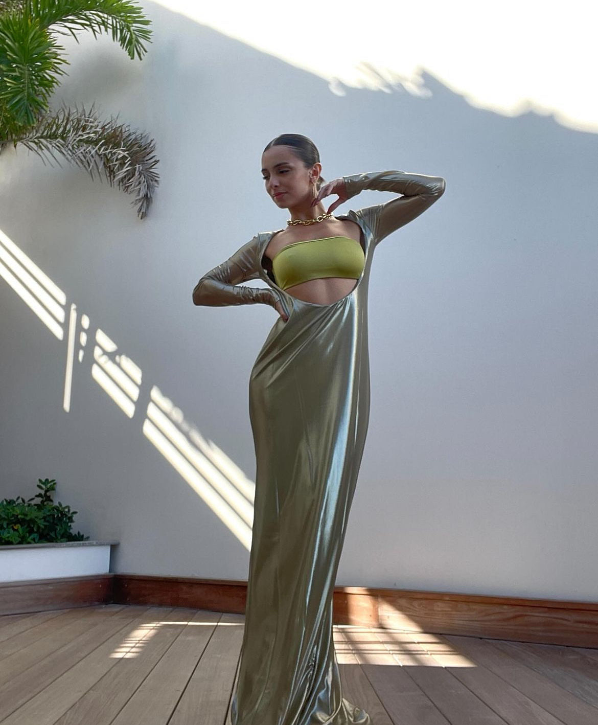 A model wearing a green, mesh maxi dress with a front cut-out and a bright color bandeau top, standing in a room with natural lighting. Baobab - Marte Stone Dress sold by two extra lives
