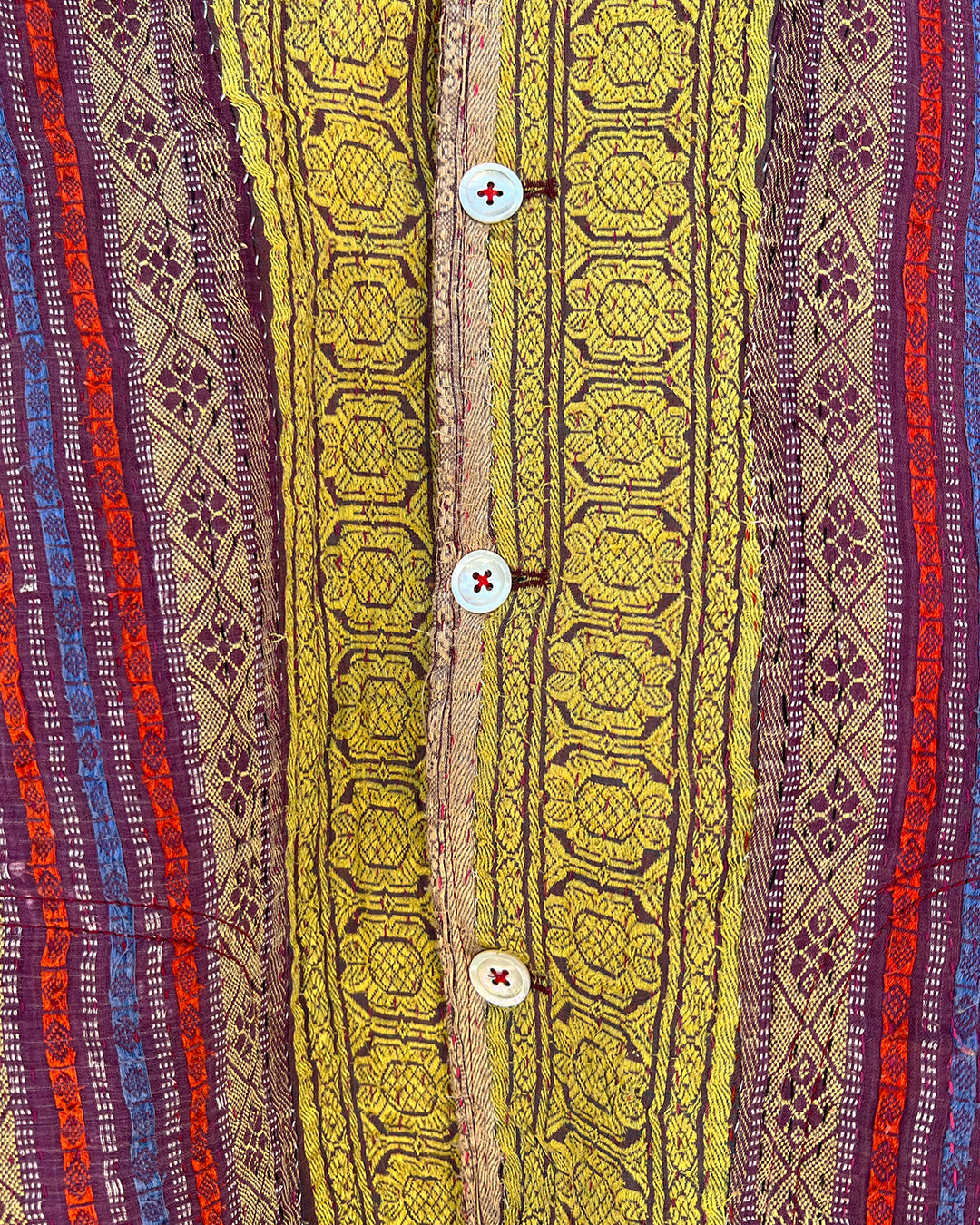 Close-up of a patterned fabric with red, yellow, and purple colors. DAY-AND-AGE-REX-JACKET-TWO-EXTRA-LIVES