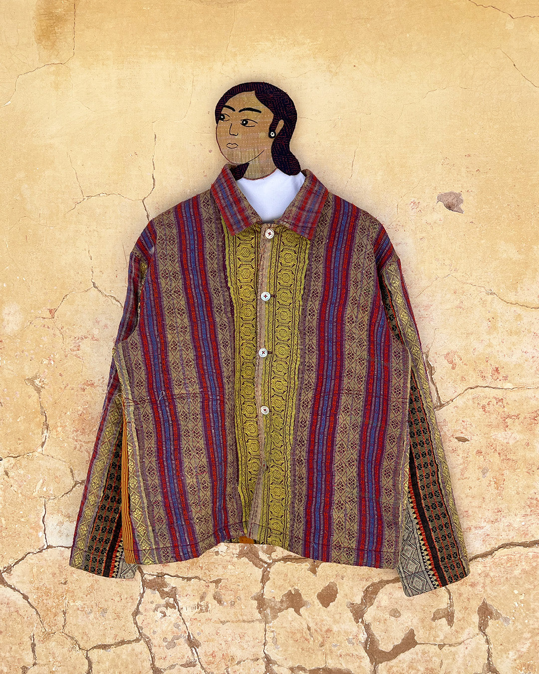 Traditional garment with intricate patterns on a textured beige DAY-AND-AGE-REX-JACKET-TWO-EXTRA-LIVESbackground