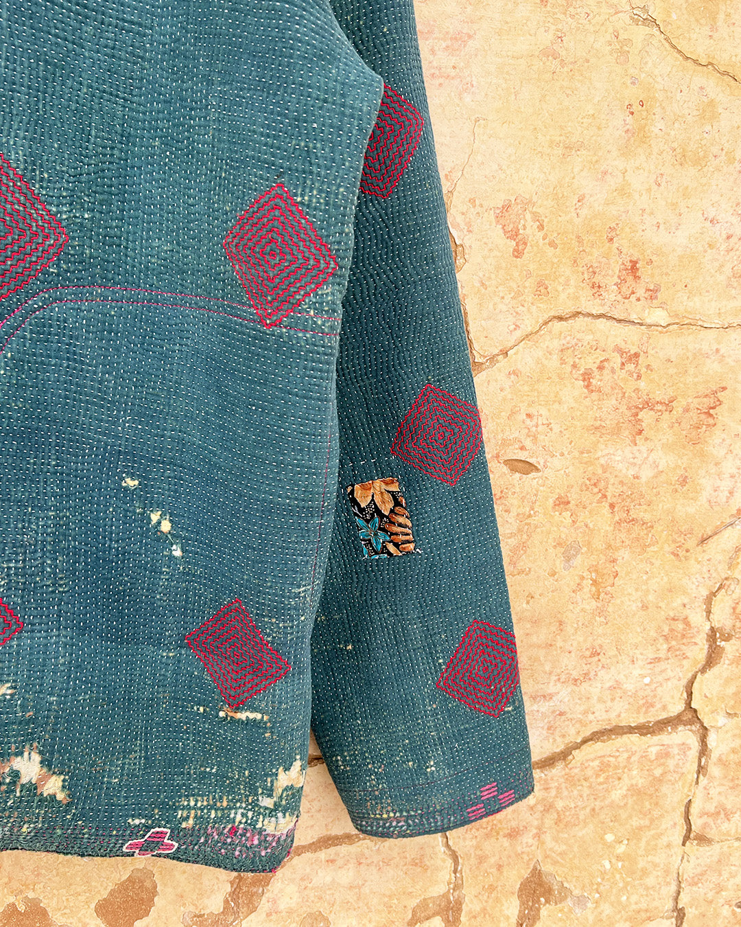 Teal fabric with red geometric patterns on a beige textured background DAY-AND-AGE-TWILIGHT-JACKET-TWO-EXTRA-LIVES