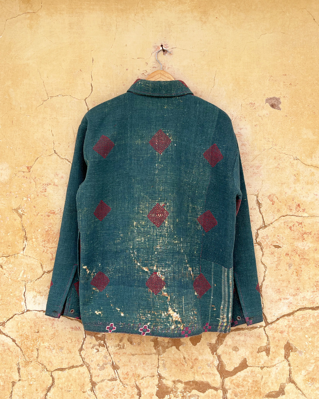 Teal jacket with red pattern on a textured beige wall DAY-AND-AGE-TWILIGHT-JACKET-TWO-EXTRA-LIVES