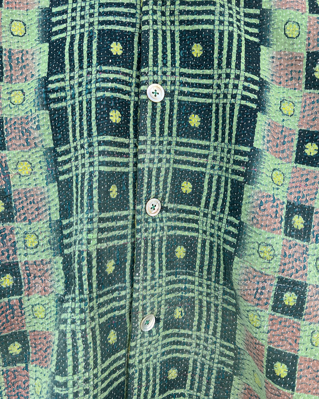 Close-up of a patterned fabric with green, pink, and black colors. DAY-AND-AGE-YAKSHI-JACKET-TWO-EXTRA-LIVES