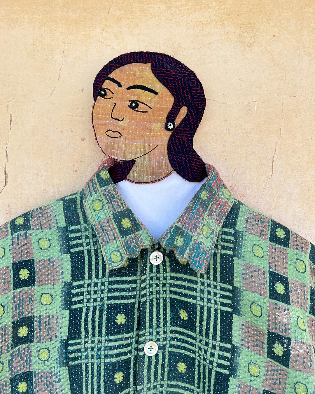 Artistic depiction of a person wearing a patterned shirt on a textured beige background DAY-AND-AGE-YAKSHI-JACKET-TWO-EXTRA-LIVES