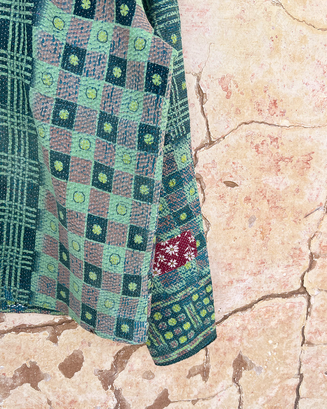 Textile with green and purple checkered pattern on a textured beige DAY-AND-AGE-YAKSHI-JACKET-TWO-EXTRA-LIVES surface