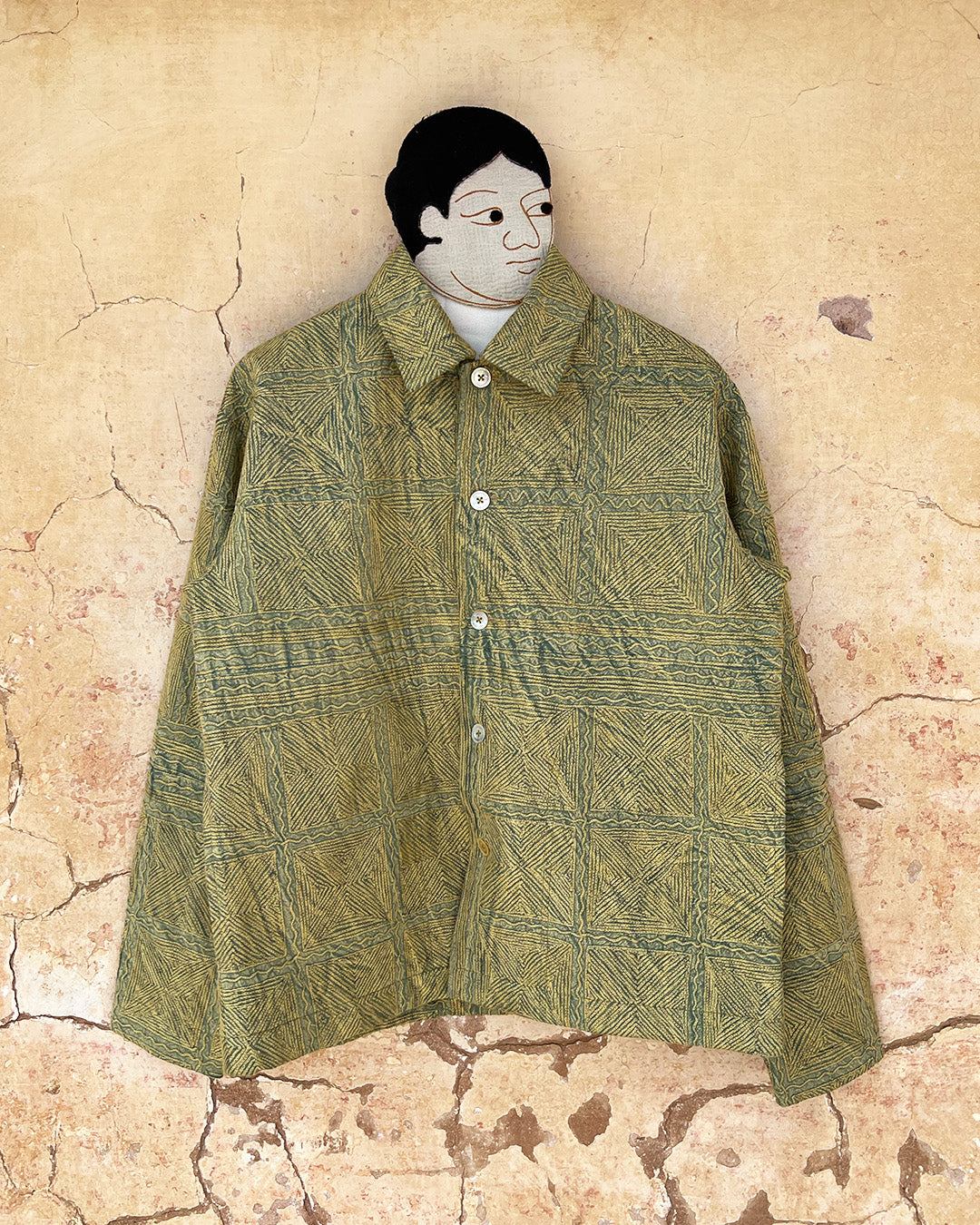 Green patterned jacket by day and age on a mannequin against a textured beige background, by two extra lives.