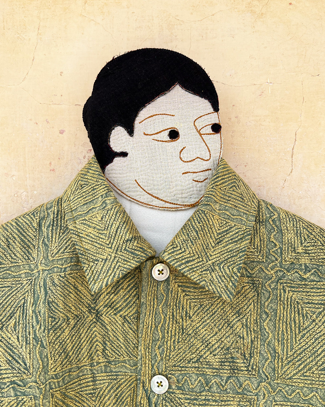 Green patterned jacket by day and age on a mannequin against a textured beige background, by two extra lives.