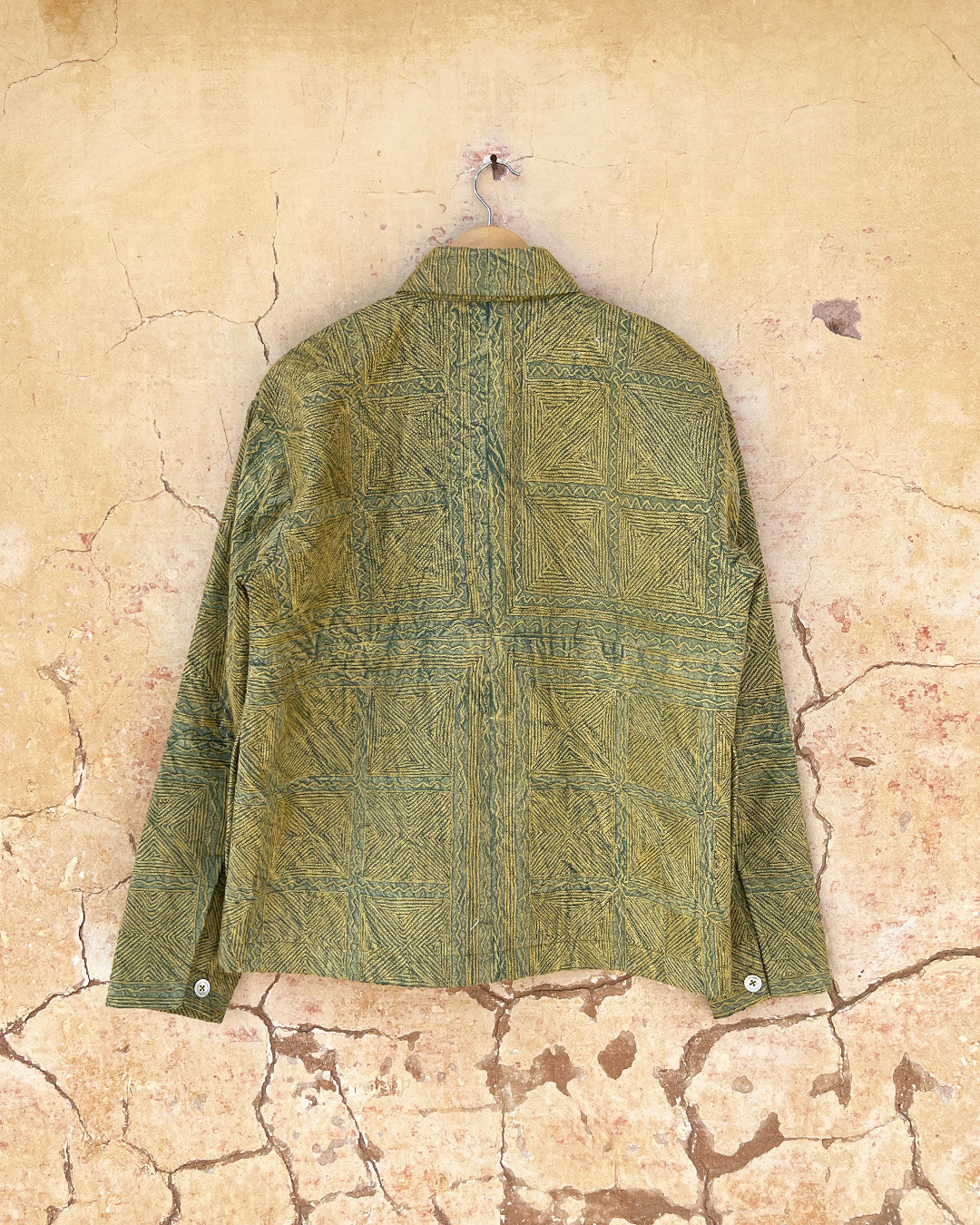 Green patterned jacket by day and age on a mannequin against a textured beige background, by two extra lives.