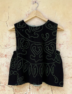 Black sleeveless relic top by day and age with heart patterns on a hanger against a textured wall.