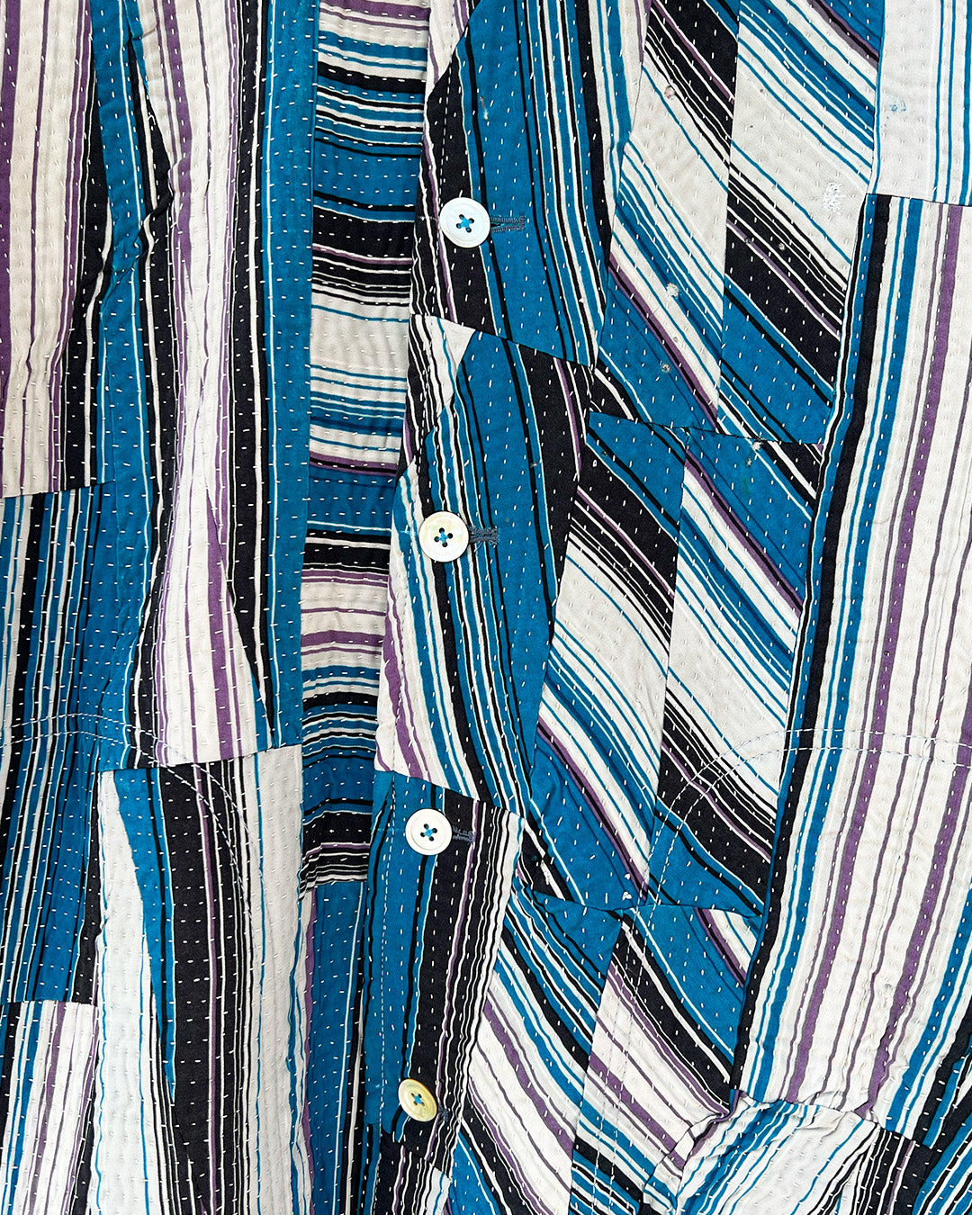 Day and age a blue and gray striped shirt on a textured beige background by two extra lives