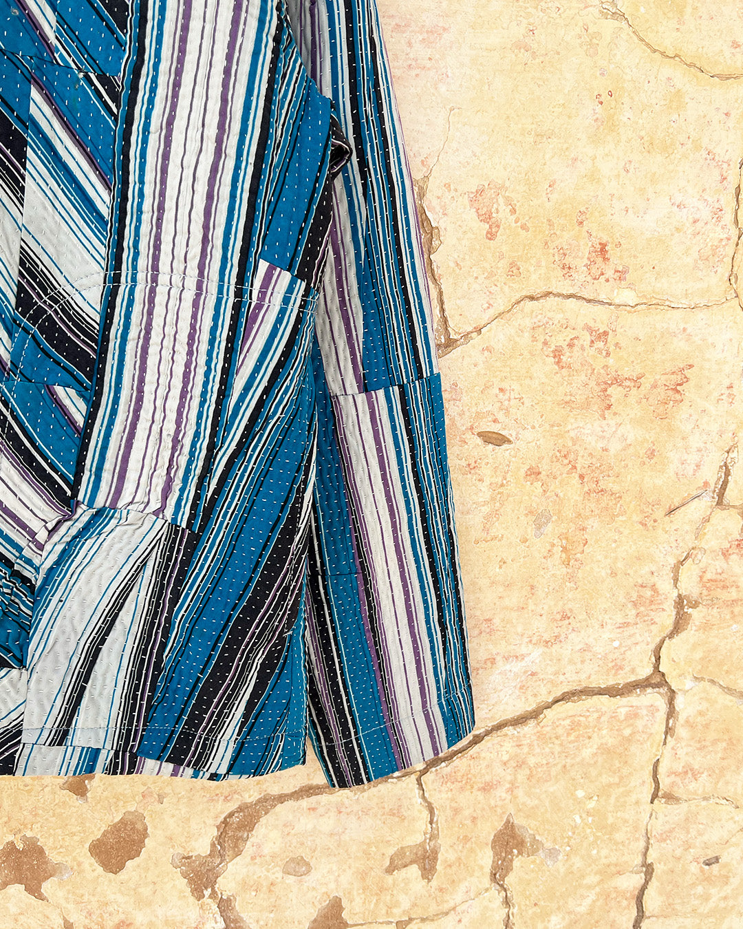 Day and age a blue and gray striped shirt on a textured beige background by two extra lives