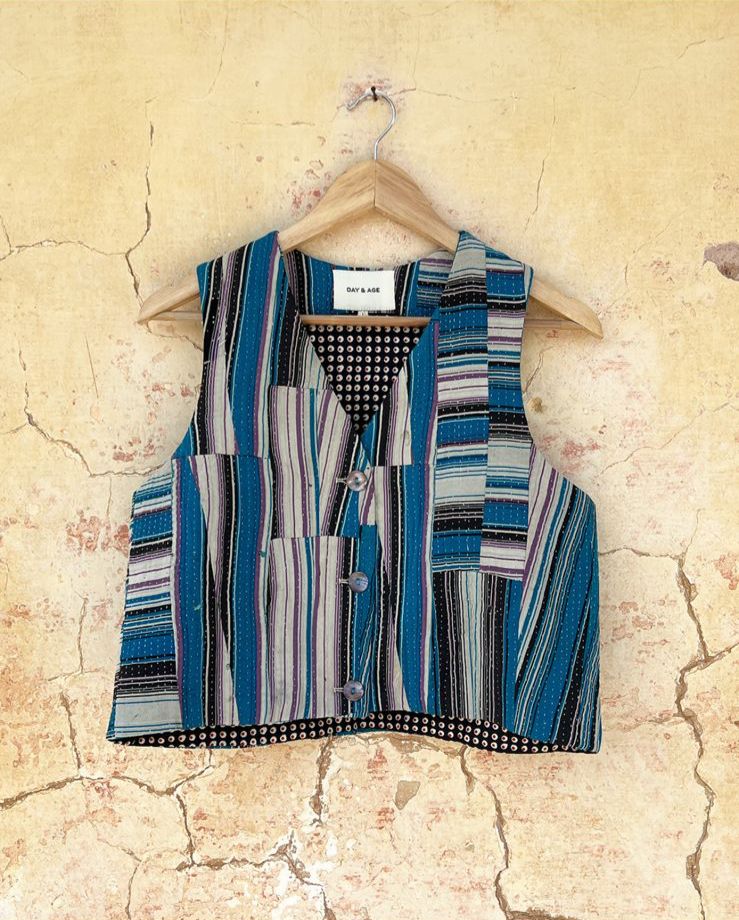 Striped shirt vest by day and age on a hanger against a textured beige wall by two extra lives