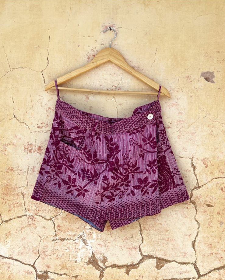 Purple patterned skort by day and age on a wooden hanger against a textured beige wall. by two extra lives