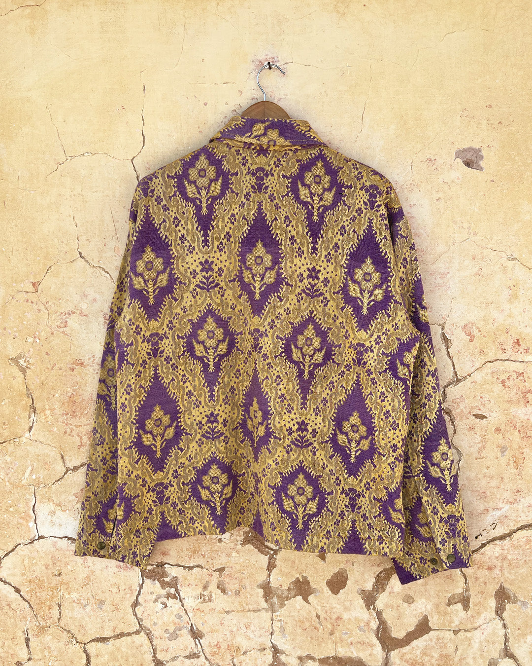 Patterned shirt jacket by day and age on a hanger against a textured wall by two extra lives