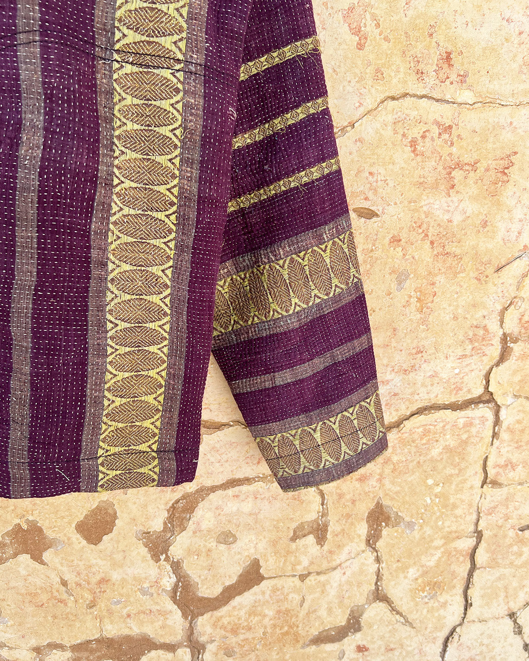 Purple fabric with gold patterns on a textured beige surface Day-and-age-regal-jacket-two-extra-lives