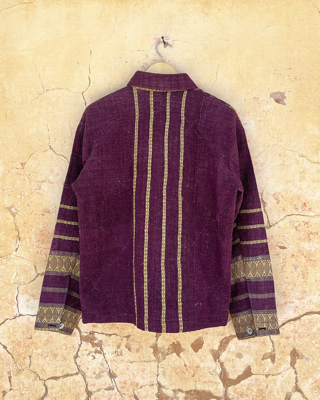 Purple jacket with gold stripes on a textured beige background Day-and-age-regal-jacket-two-extra-lives