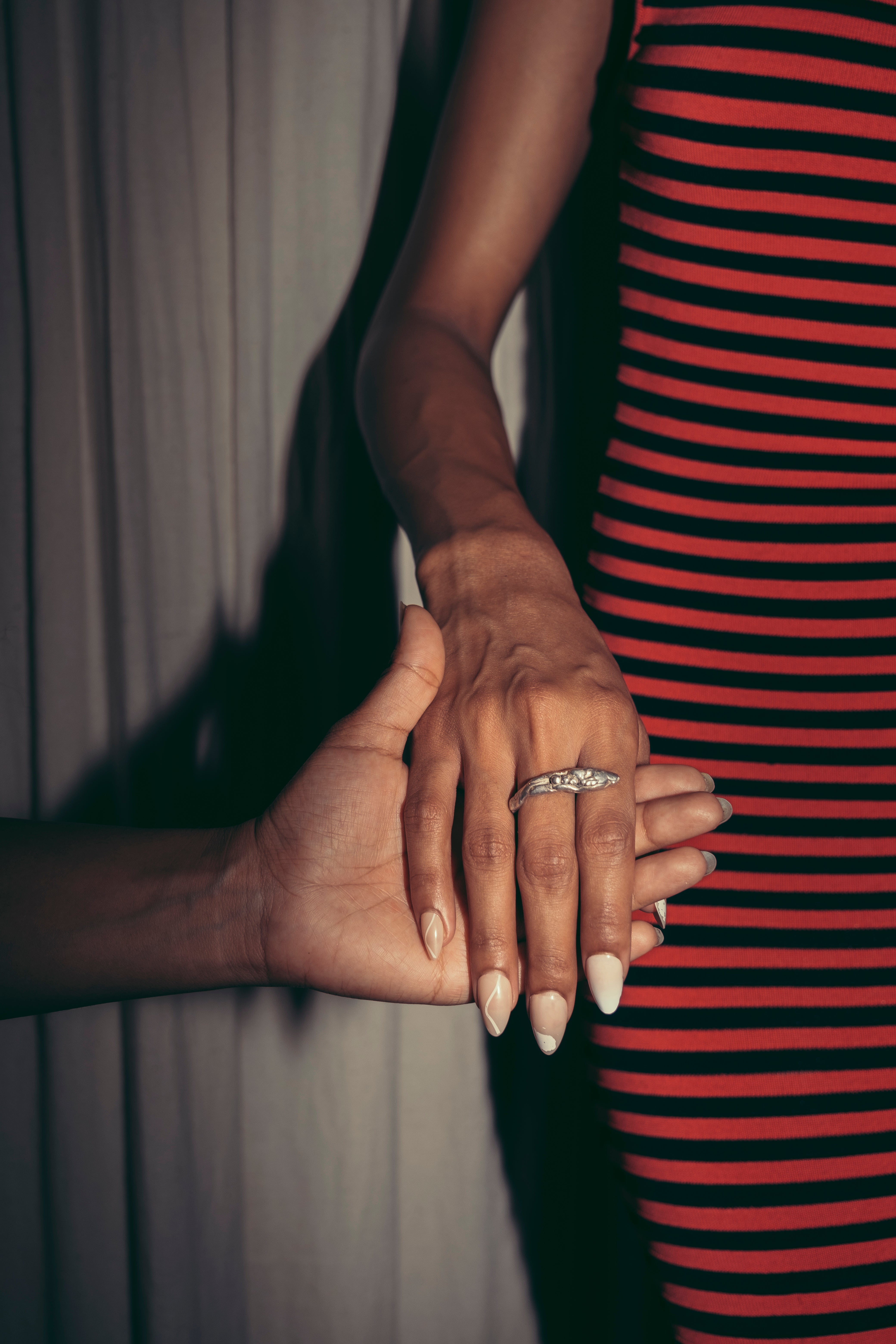 A close-up image of a snake ring on a person's finger, with the rest of the hand and arm partially visible against a striped background. Ex Nihilo - Snake Ring sold by two extra lives