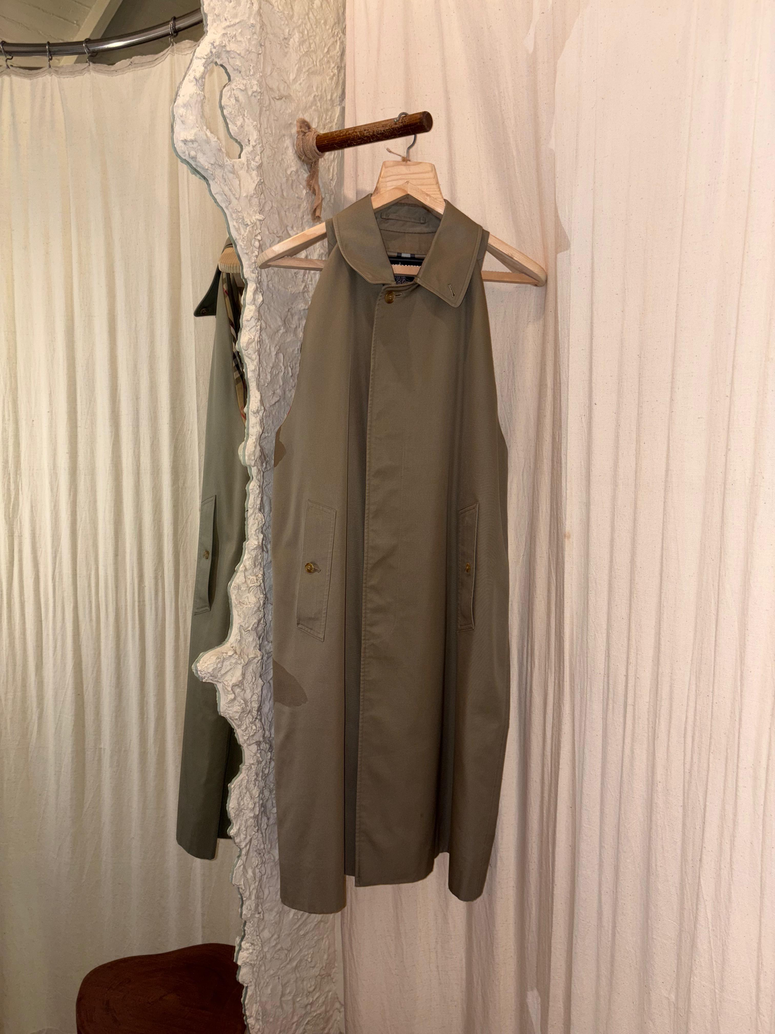 Green DRESS hanging on a wooden hanger against a white curtain 
From The Mind - Upcycled Burberry Dress background