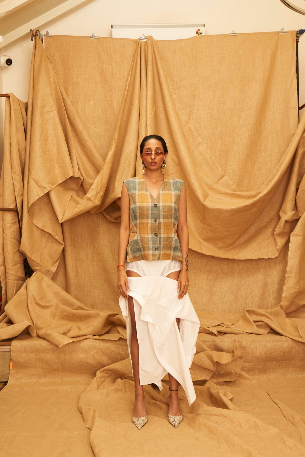 Woman standing in front of beige curtains wearing a checkered vest from Jill Sanders sold by Two Extra Lives