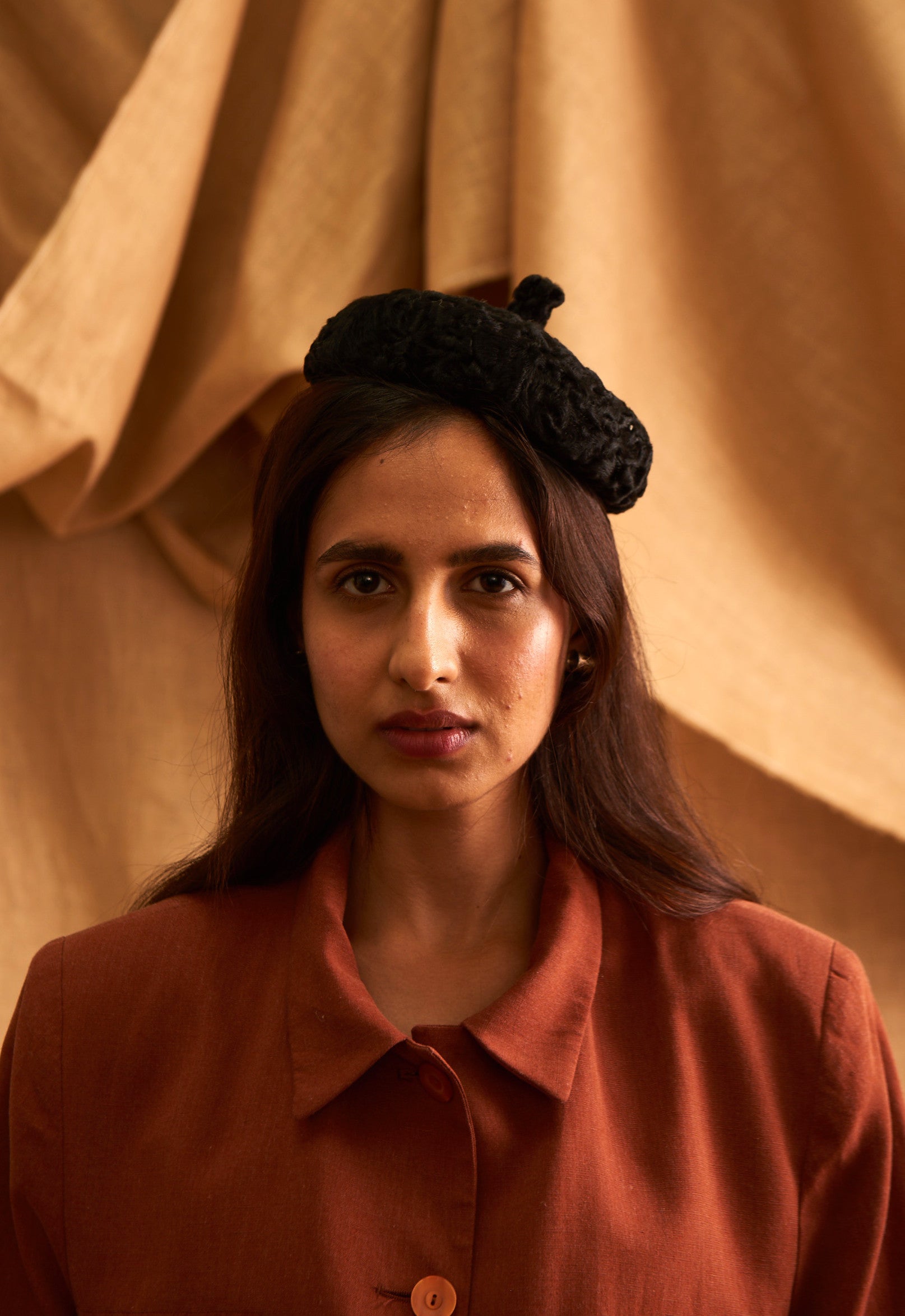 A person wearing a black textured beret with a bow detail, in front of a beige background. Kitty Comet - Noire Texture Beret sold by two extra lives