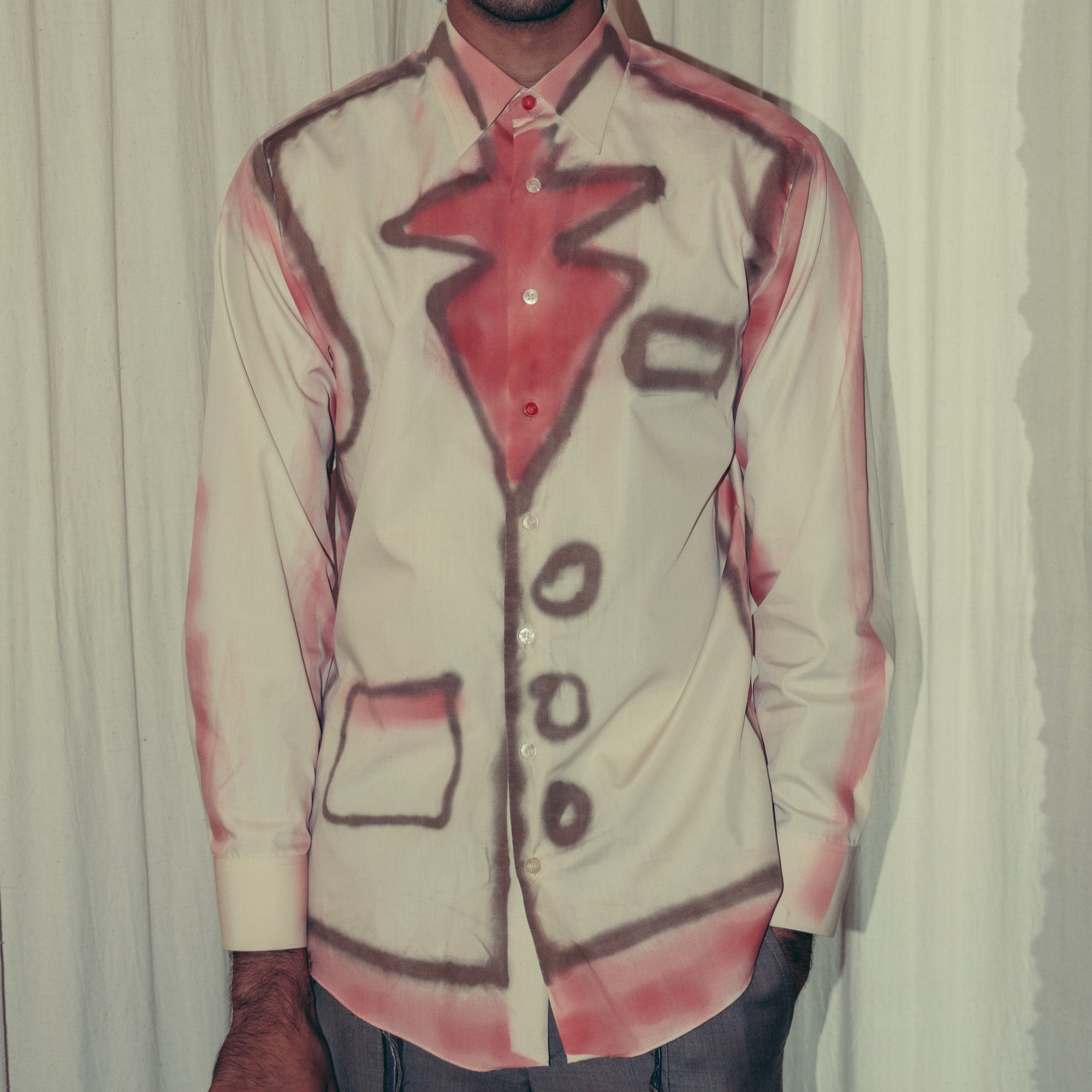 A person wearing a pink oversized  shirt with screen printing on the front and back, featuring a geometric design. Kuta House - Watercolour Shirt sold by Two extra lives