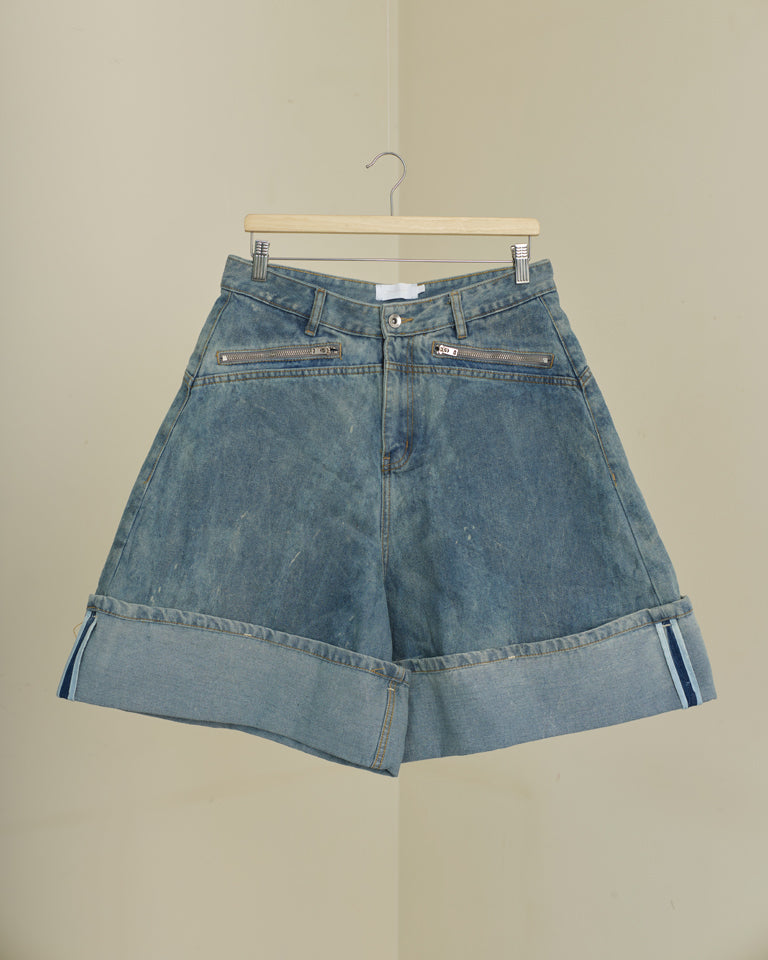 Blue denim shorts on a hanger against a beige background