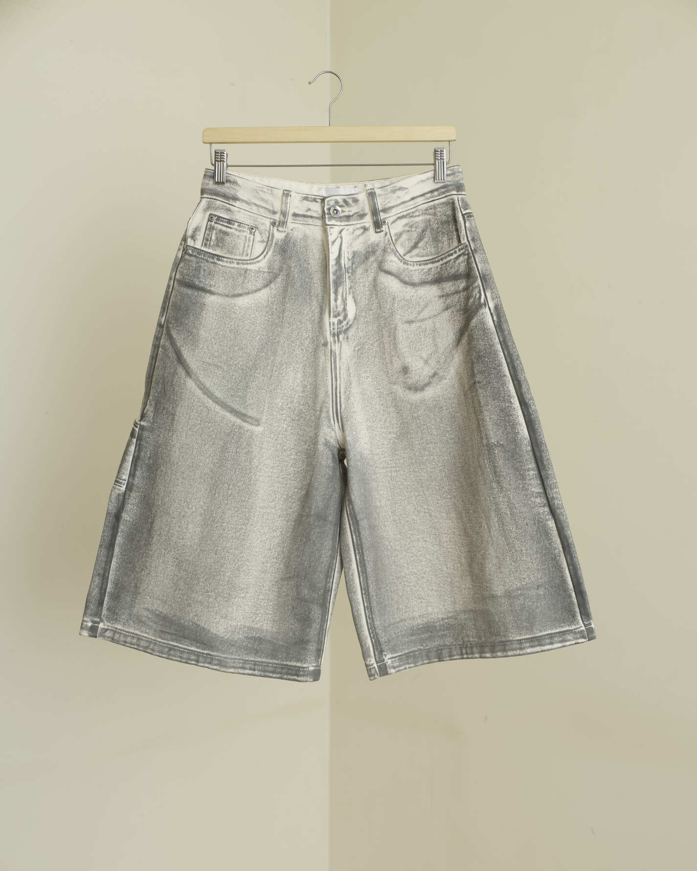 Gray denim shorts on a hanger against a beige background