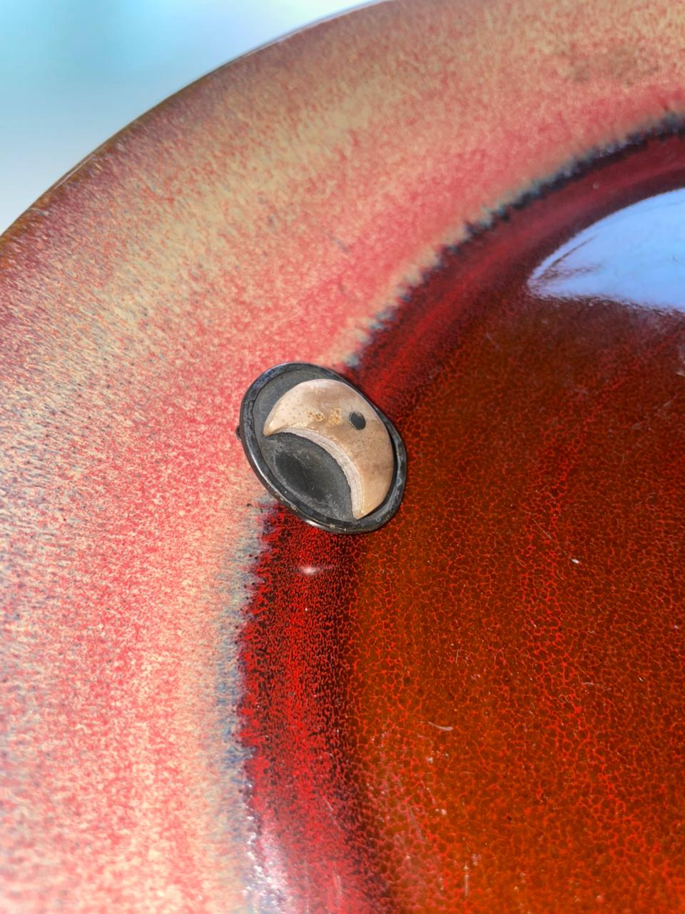 Close-up of a ceramic bowl with a textured surface and a small circular object inside. Peca-Joyería-Poética-Moon-Stud-two-extra-lives