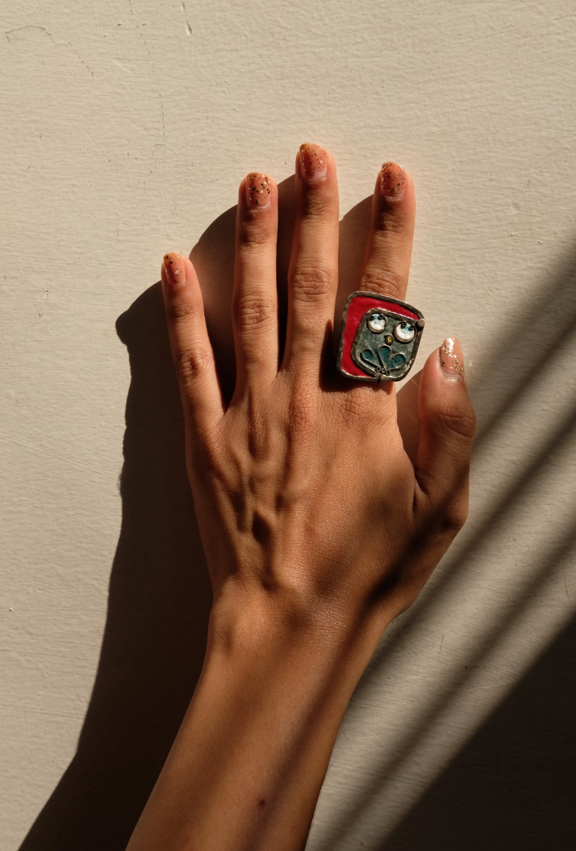 A handcrafted silver ring with coral-inspired design and vibrant accents, worn on a person's finger. Peca Joyería Poética - Coral Ring sold by two extra lives
