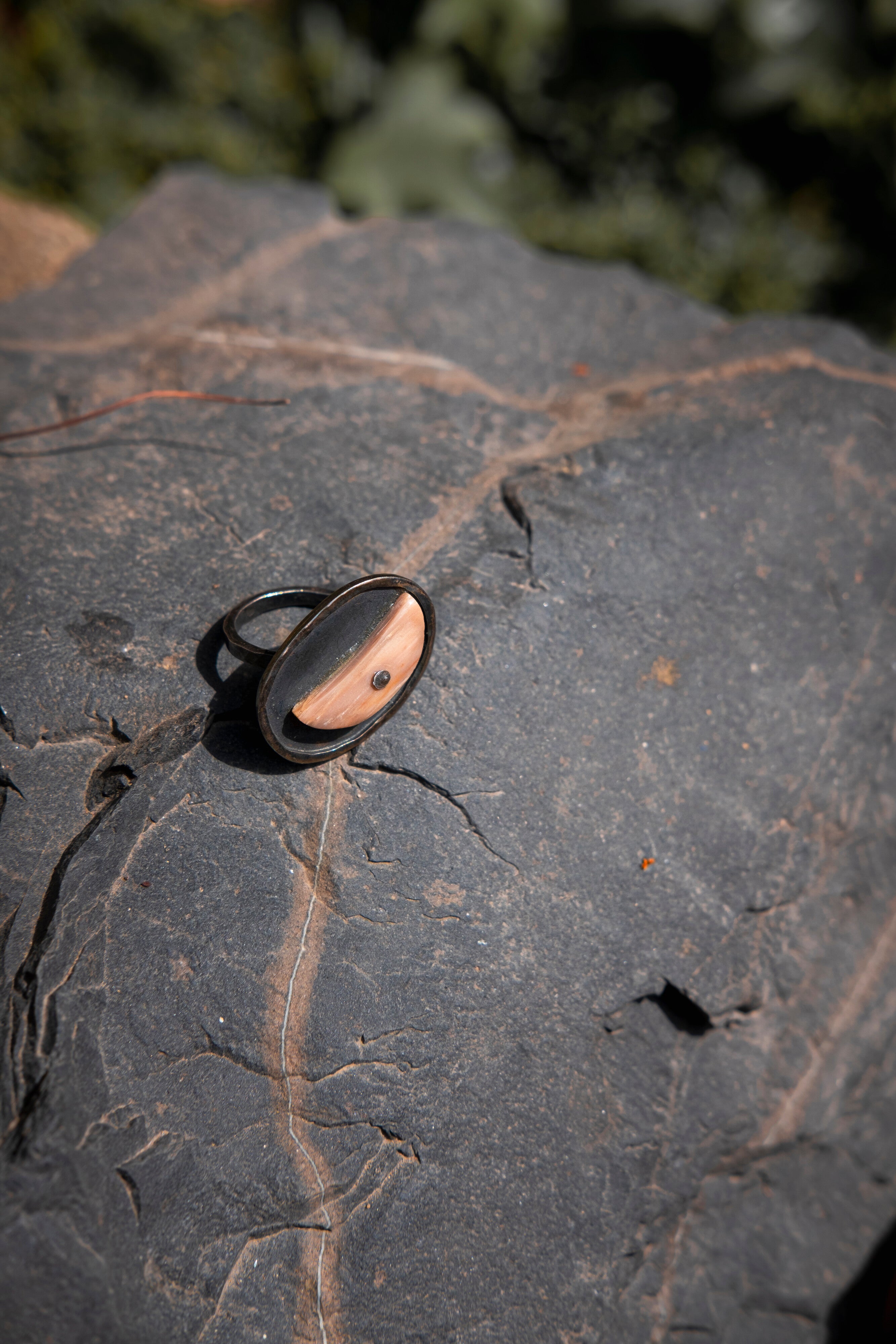 A half moon ring with a silver and wood design, placed on a dark, textured surface. Peca Joyería Poética - Half Moon Ring sold by two extra lives