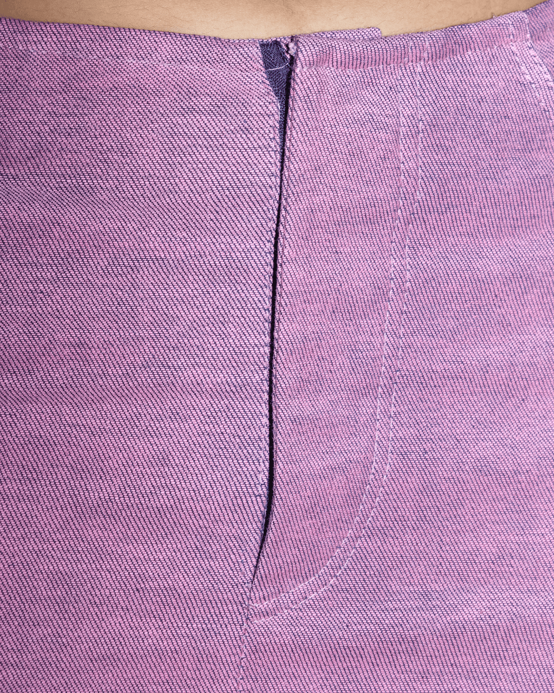 Close-up of a lavender-purple textured fabric garment with a central seam and a small portion of skin visible at the top edge.