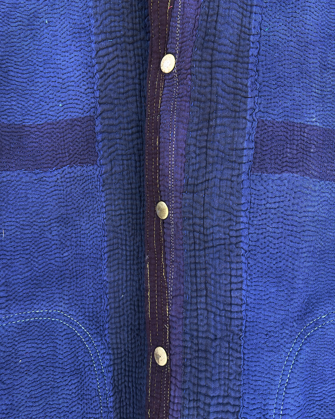 Close-up of a blue textured fabric with gold buttons and a brown border. day-and-age-marina-jacket-two-extra-lives
