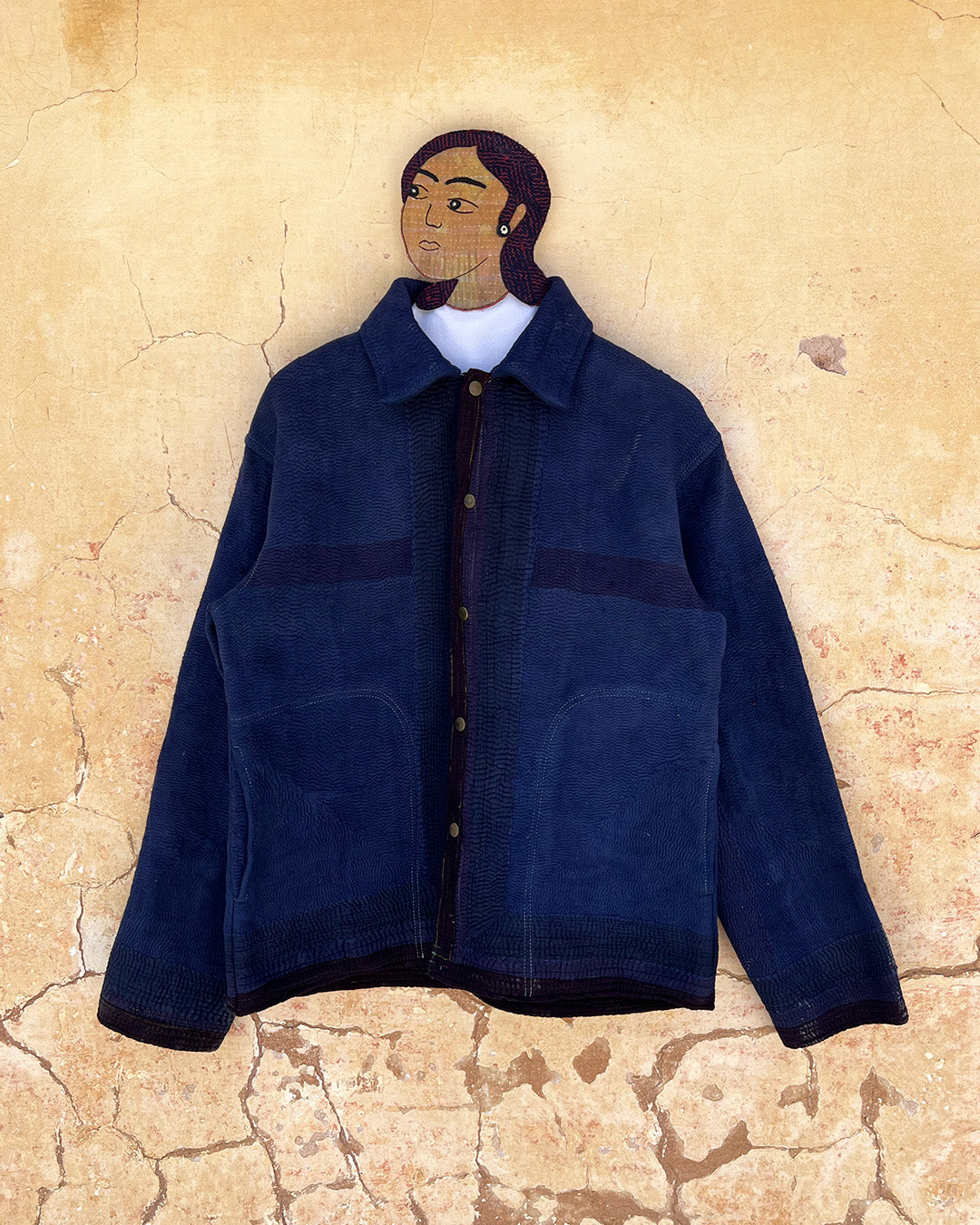 Blue jacket on a mannequin against a textured beige wall day-and-age-marina-jacket-two-extra-lives