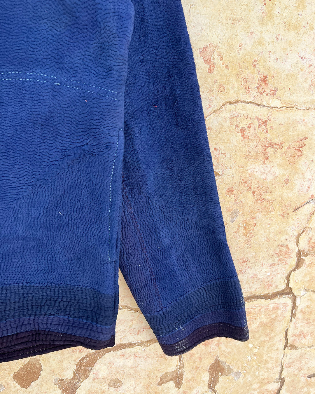 Blue textured towel on a beige textured surface day-and-age-marina-jacket-two-extra-lives