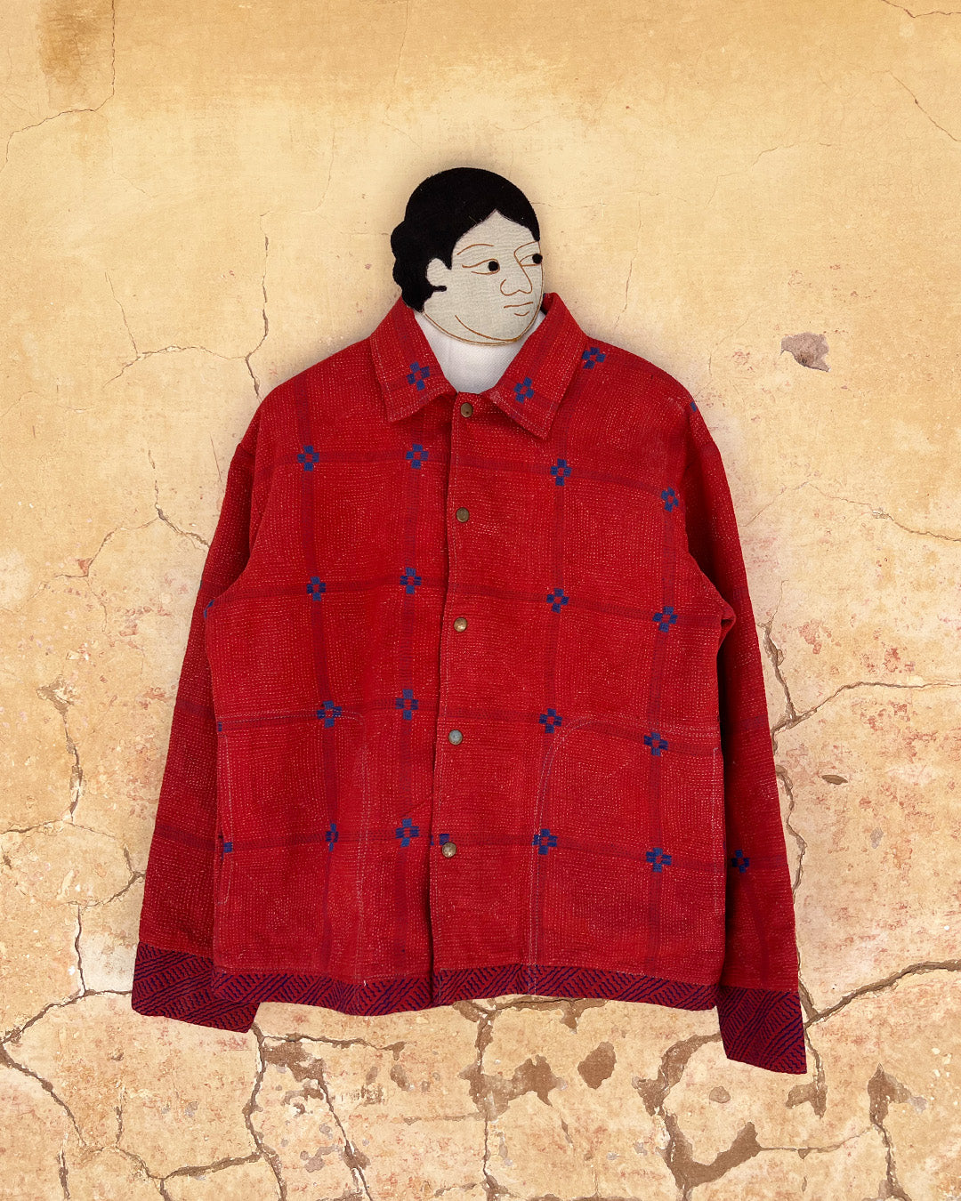 Red jacket with blue patterns on a textured beige background day-and-age-steaam-angine-jacket-two-extra-lives