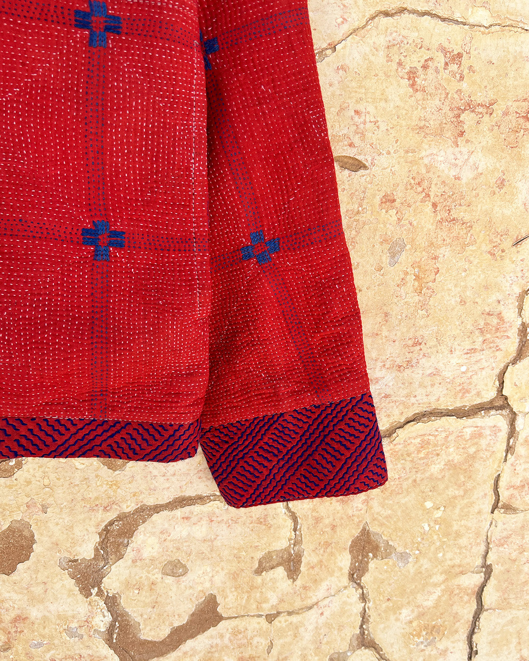 Red fabric with blue patterns on a textured beige surface day-and-age-steaam-angine-jacket-two-extra-lives