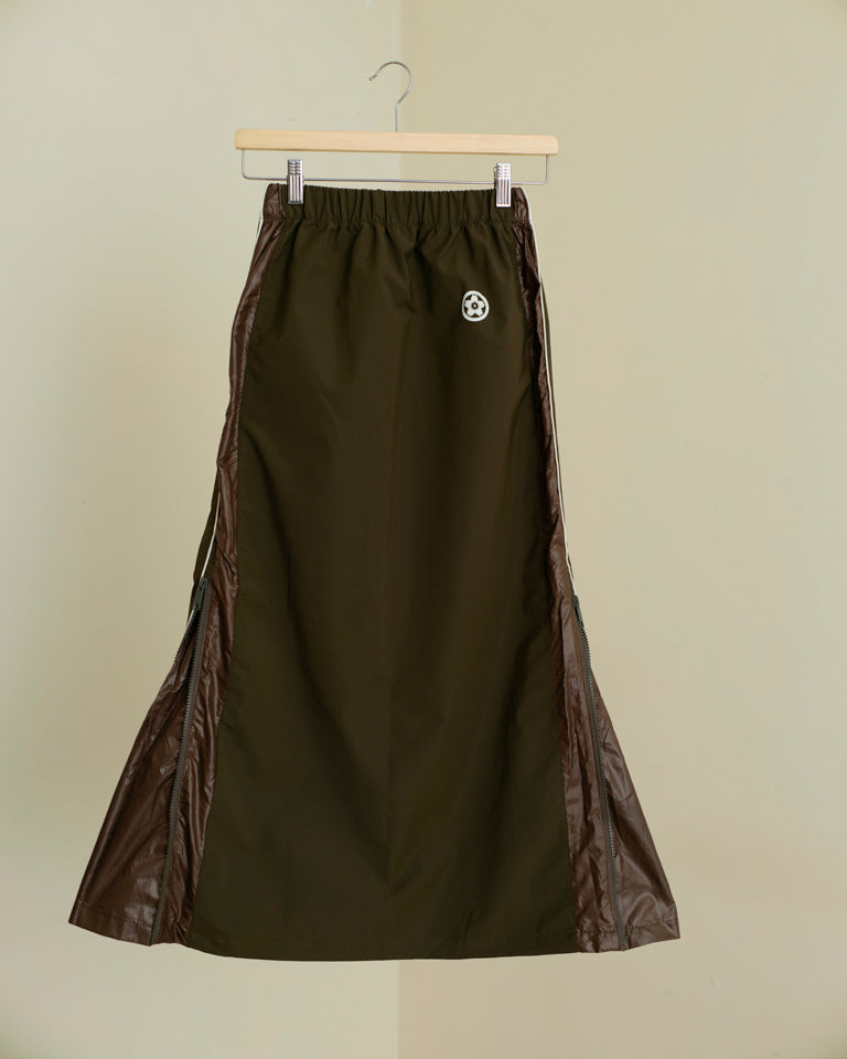 Brown skirt with leather accents on a hanger against a beige background